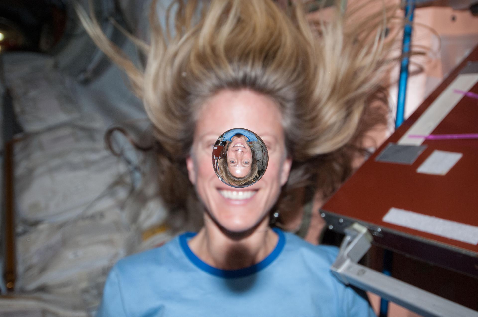 A female astronaut on the space station demonstrating a water droplet in zero gravity