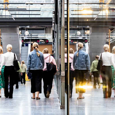 Människor promenerar i ett ködcentrum med ryggen mot kameran.