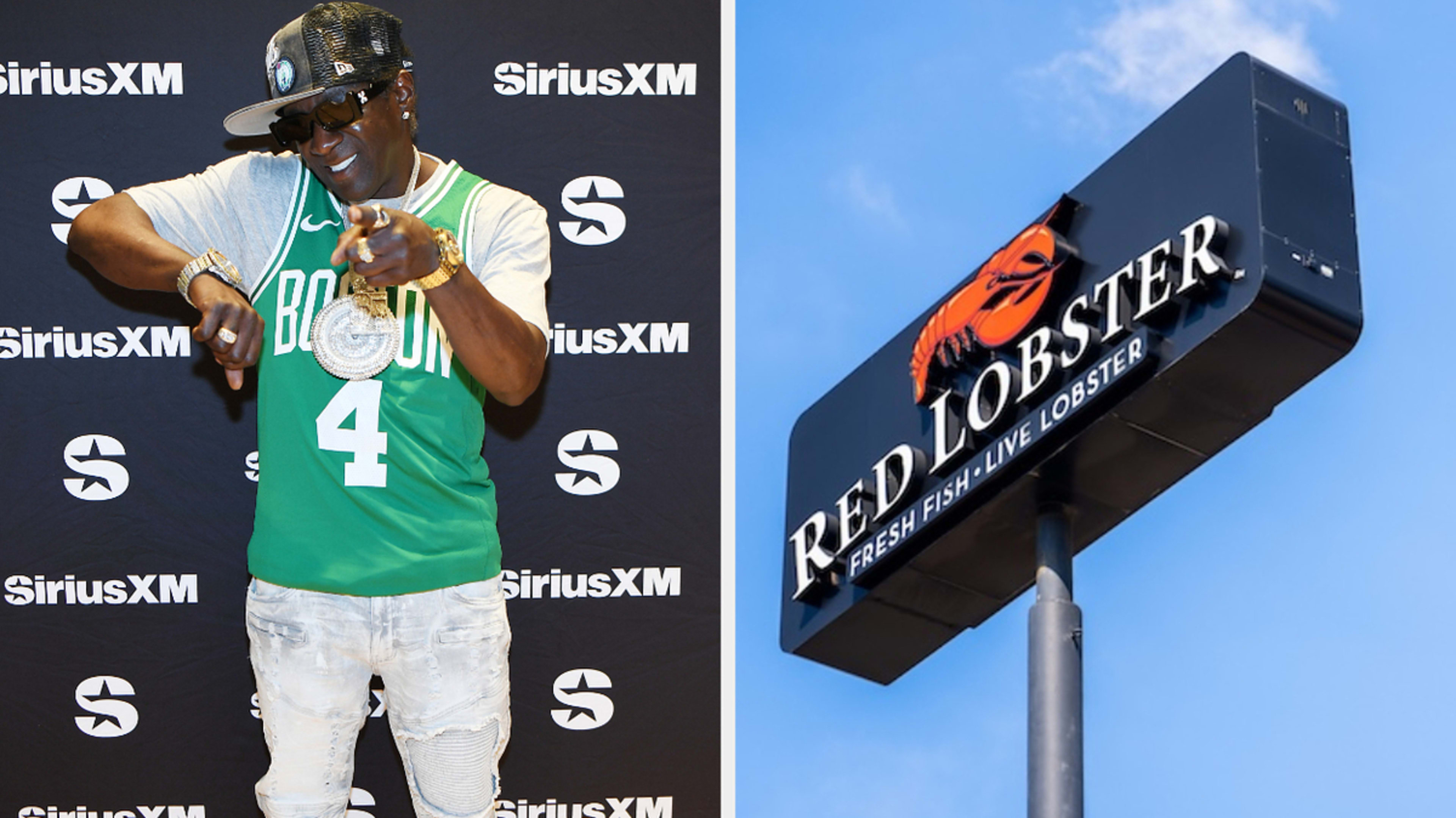 Flavor Flav poses at a SiriusXM event in a Boston basketball jersey and cap. Next to him is a Red Lobster restaurant sign