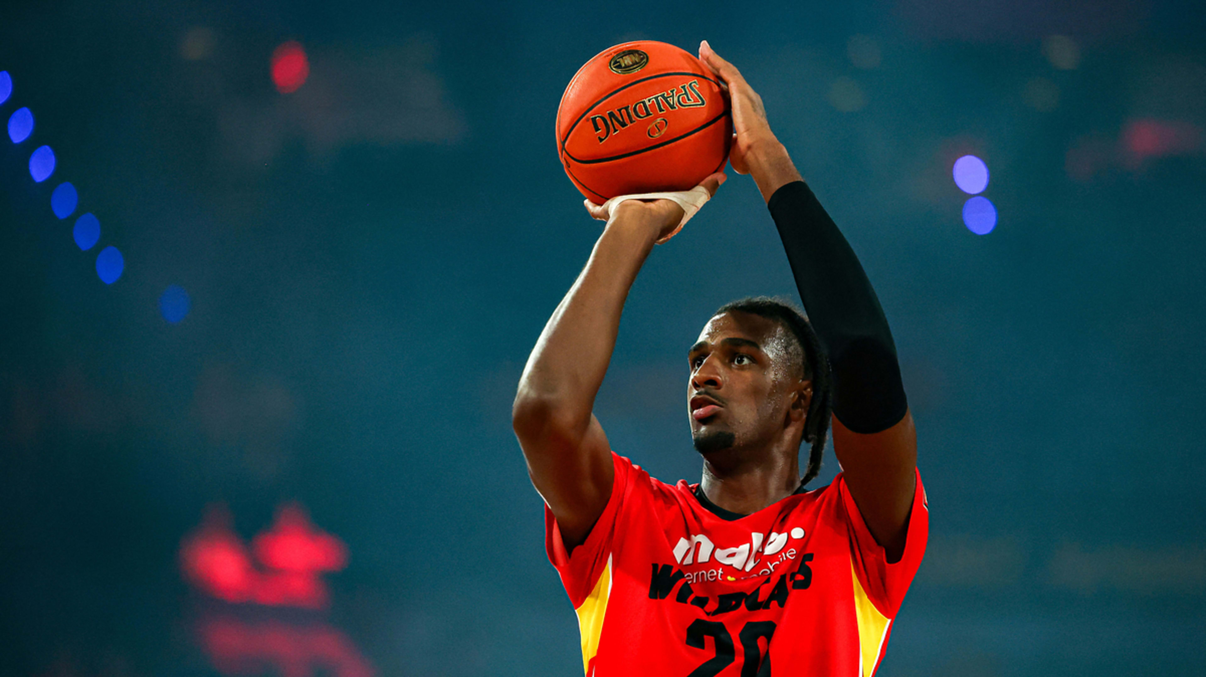 A basketball player is about to take a shot during a game. He wears a red and yellow jersey with the number 20