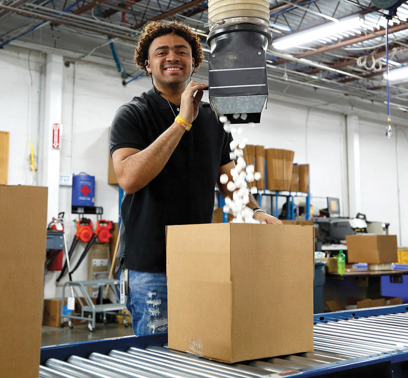 Warhouse employee filling package with biodegradable packing peanuts