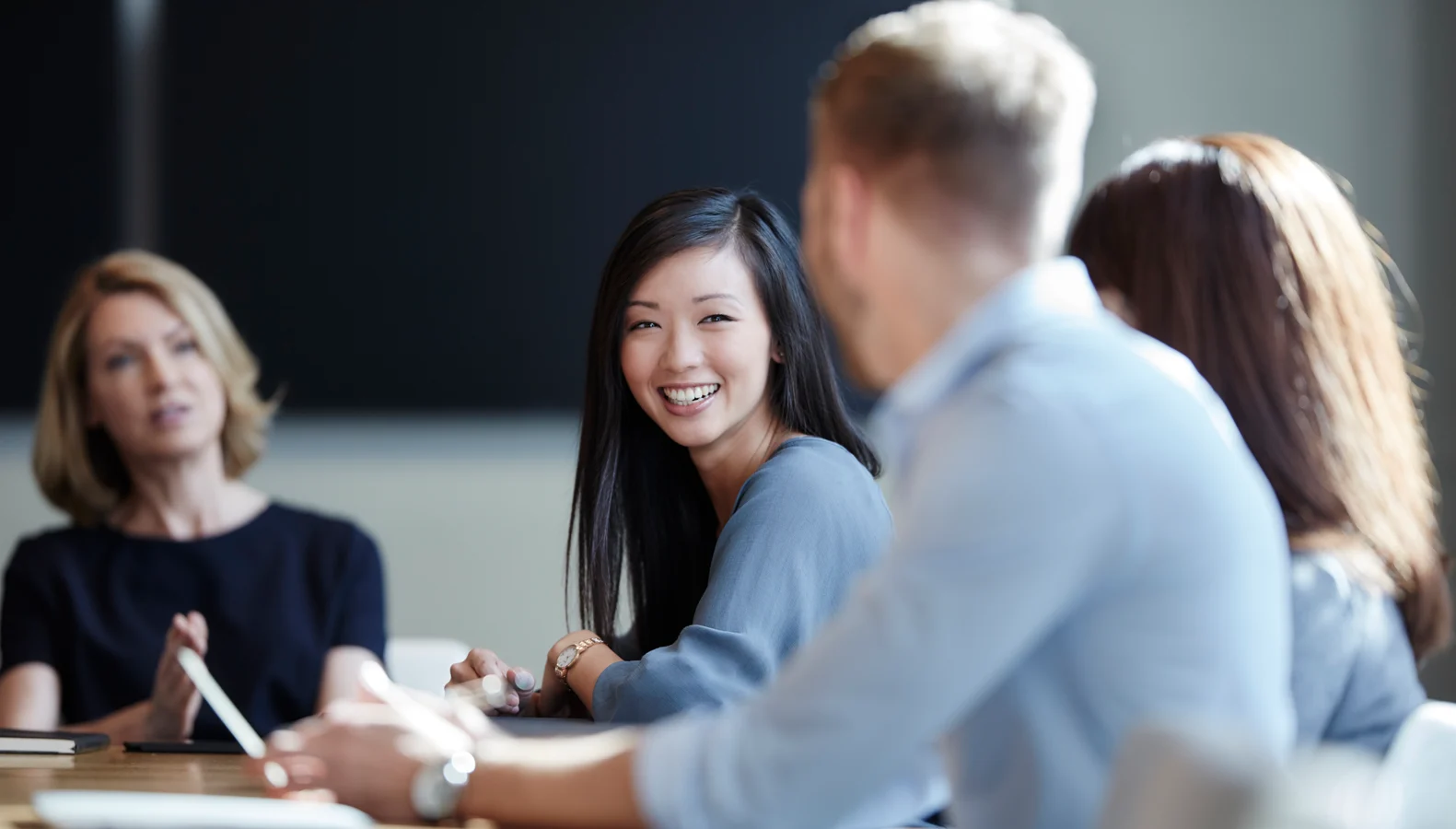 A person in a conference room meeting with three other people