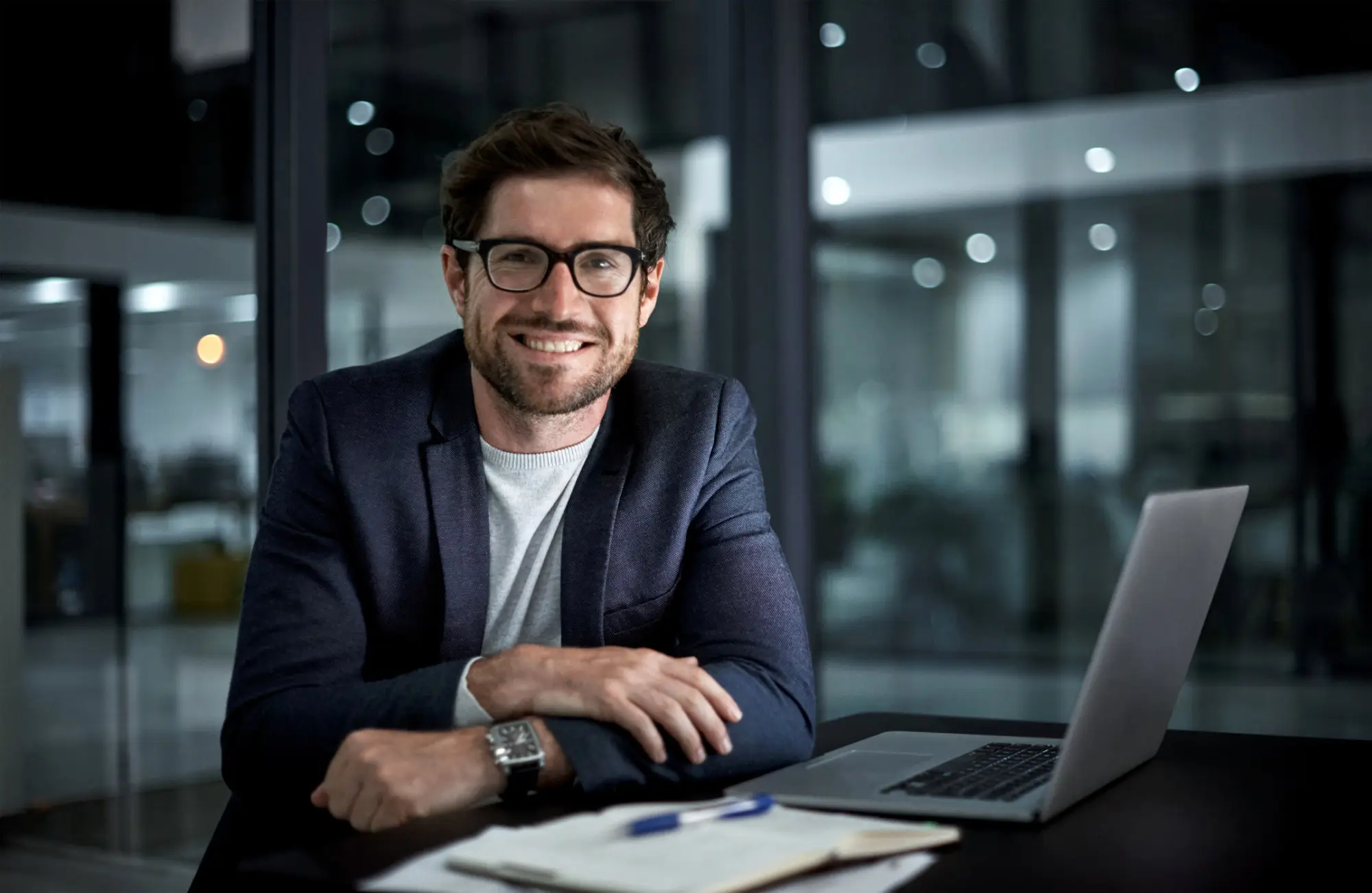 A smiling businessman sitting in front of a computer