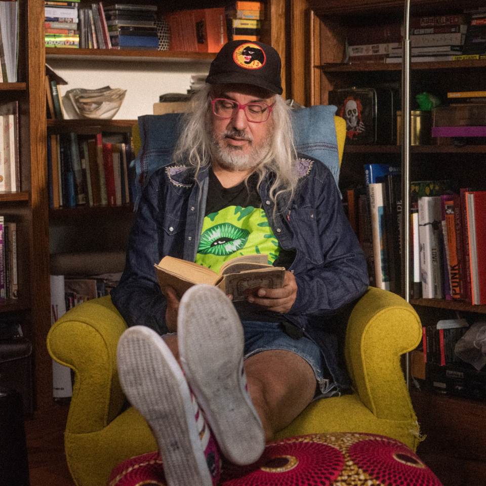 J Mascis sentado en una silla leyendo un libro.