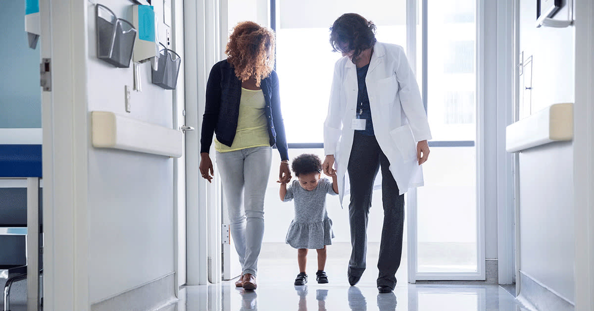 doctor holding child's hand with mother