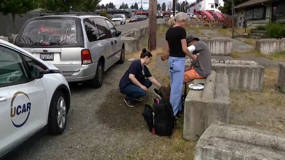 two nurses check a man's blood pressure on the side of street