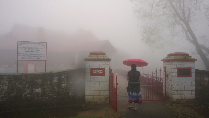 A woman walks inside a building with an umbrella in the mist-covered town of Cherrapunjee in India's Meghalaya state. Cherrapunjee, or Charrapunji, is a subdivisional town in the East Khasi Hills district in Meghalaya. It is credited as being the wettest place on Earth, although nearby Mawsynram currently holds that record. Cherrapunji still holds the all-time record for the most rainfall in a calendar month and in a year.