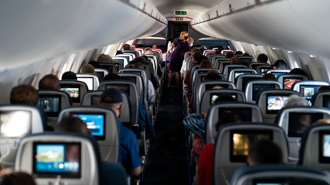 FILE - Flight attendants hand out refreshments to a packed Delta Airlines flight traveling from Ronald Regan National Airport to Minneapolis-Saint Paul International Airport on Friday, May 21, 2021.