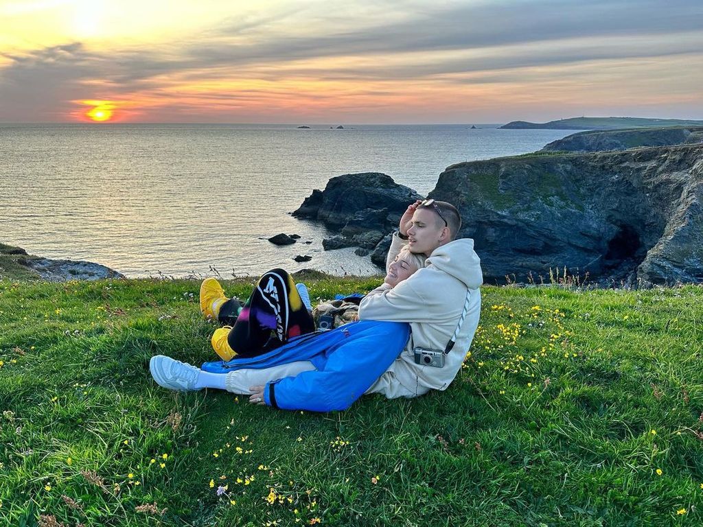 Romeo Beckham and Mia Regan sitting on top of a cliff 