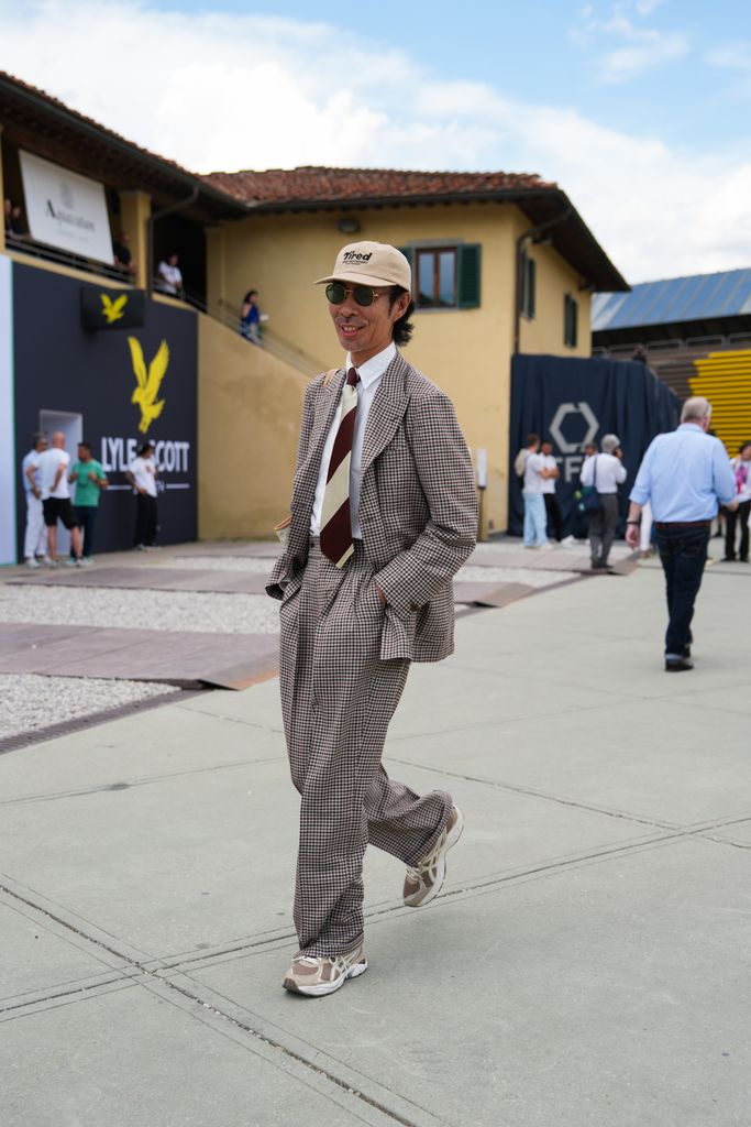 A guest wearing a brown and beige checkered suit is seen during Pitti Immagine Uomo 106