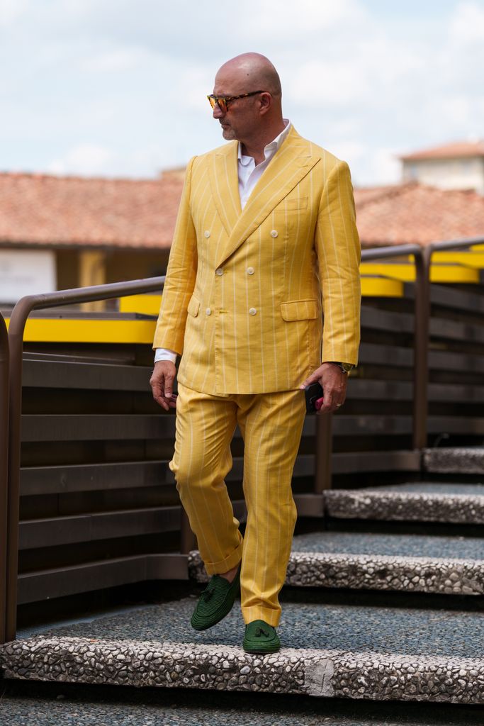 A guest wearing a yellow double-breasted suit, green woven loafers is seen during Pitti Immagine Uomo 106