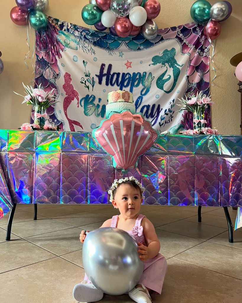 little girl sat on floor holding balloon 