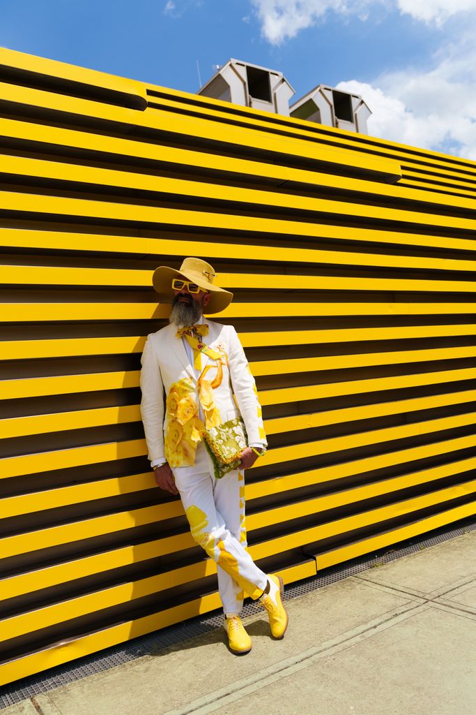 A guest wearing a wide-brimmed yellow hat, a white suit jacket with large yellow patterns is seen during Pitti Immagine Uomo 106 on June 11