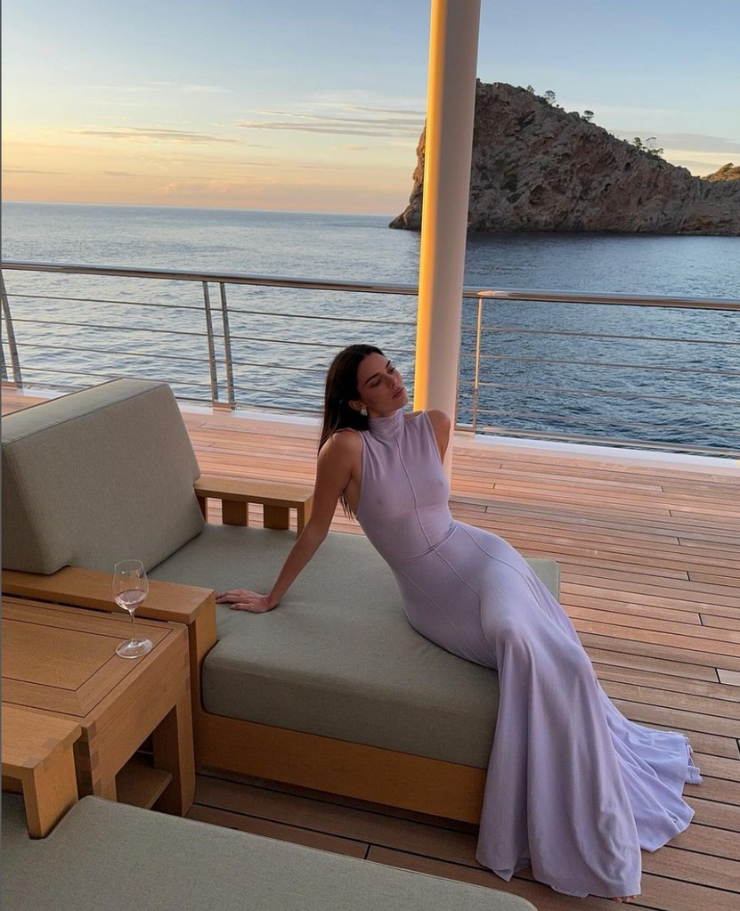 While enjoying a girls' trip in Mallorca, Spain, with her younger sister Kylie, Kendall Jenner is  the yacht wearing a lilac dress by Khaite, while drinking wine
