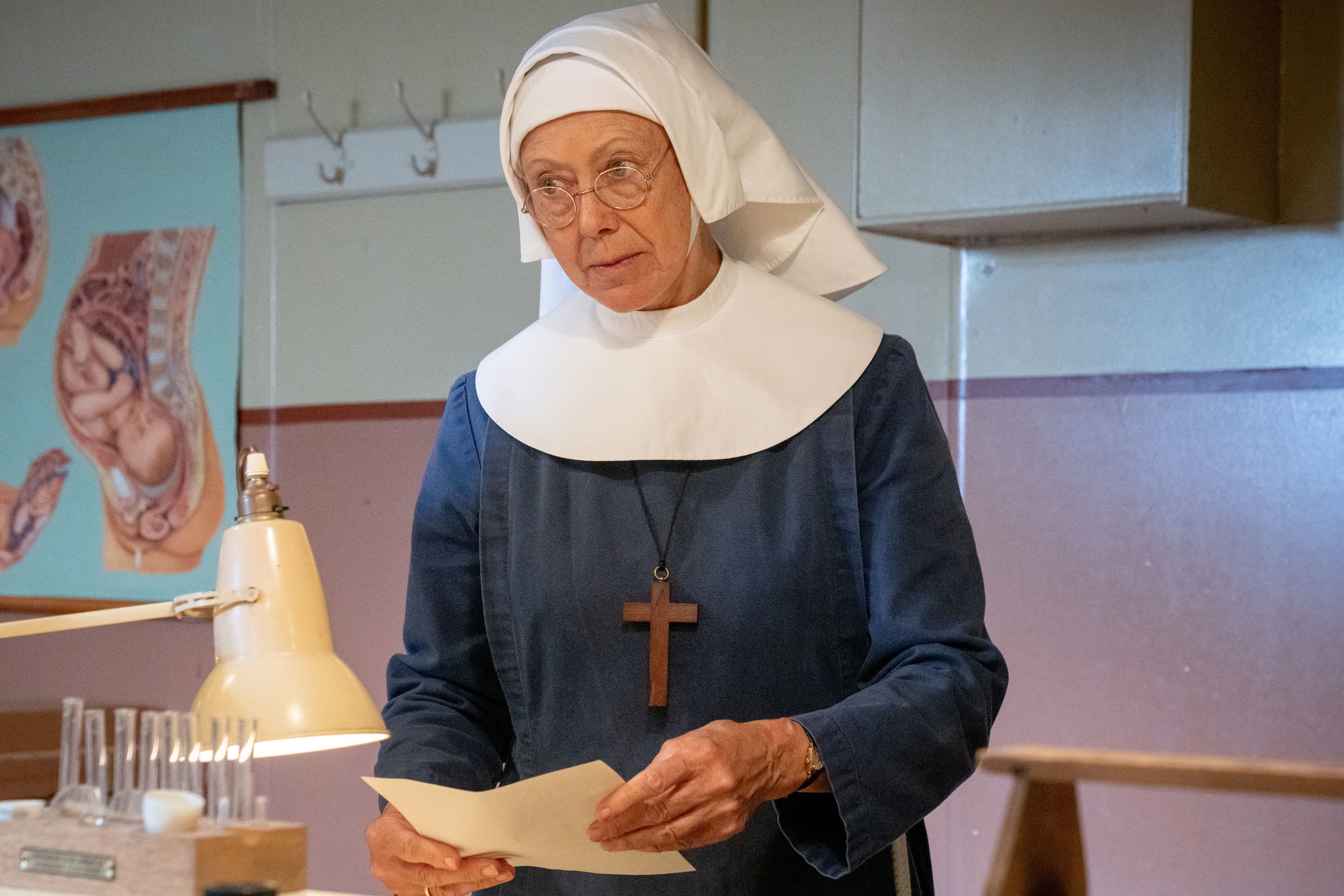 Sister Julienne in the maternity ward wearing her uniform. She's holding a letter and looks very concerned