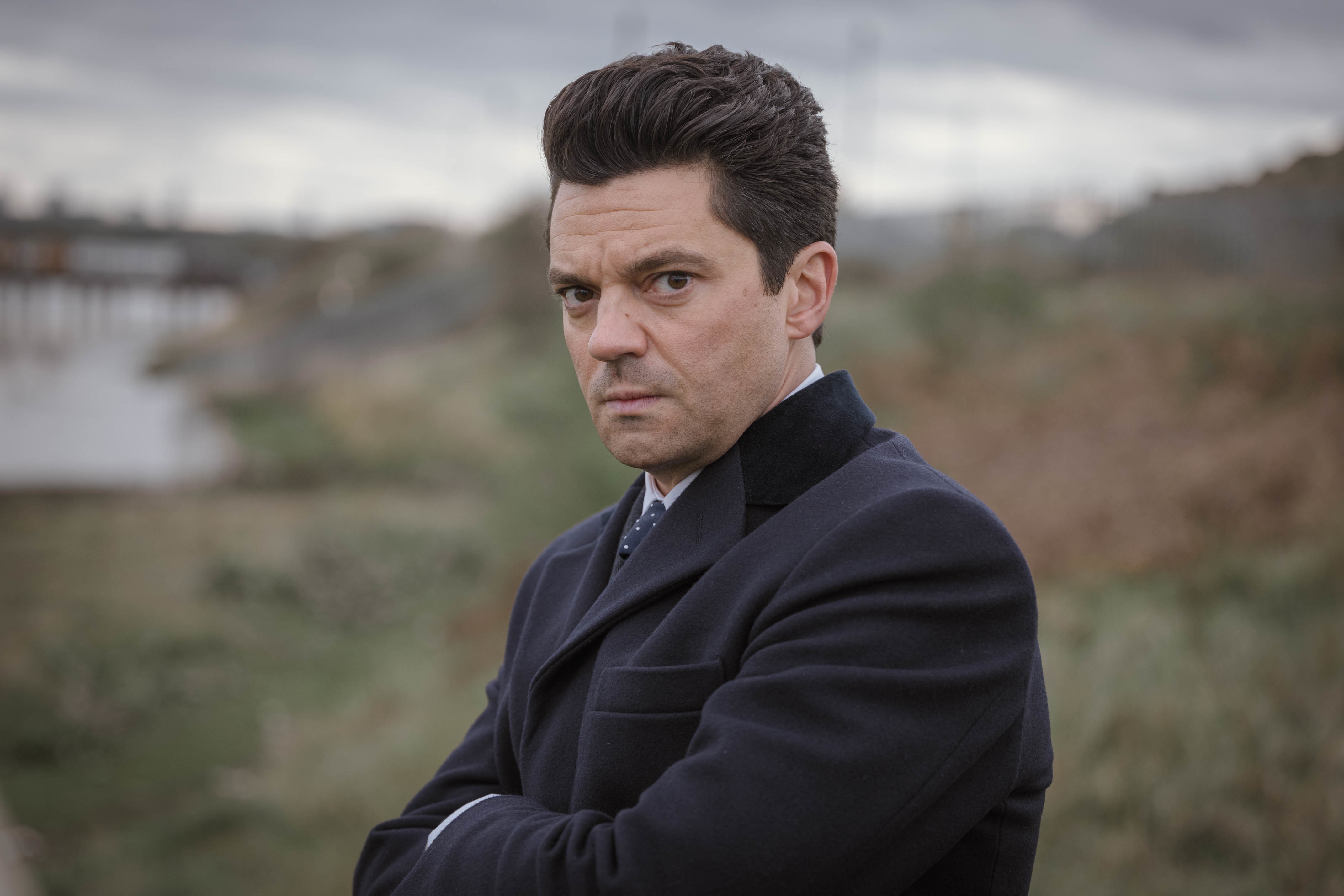 Edwyn Cooper (Dominic Cooper) in The Gold wearing a suit, looking into camera