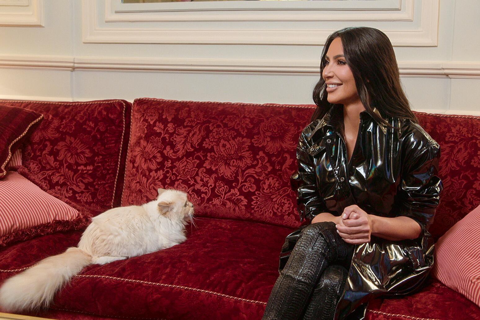 Kim Kardashian and Choupette sitting on a sofa in The Kardashians.