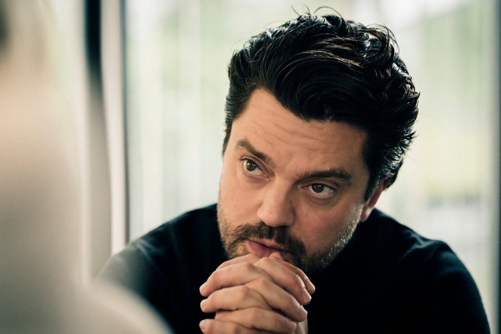 Dominic Cooper as Jon Fallow in Suspect season 2 leaning forward and clasping his hands in front of him, looking stressed.