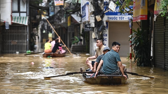 Des gens sur des bateaux de fortune dans les rues d'une ville inondée au Vietnam. 