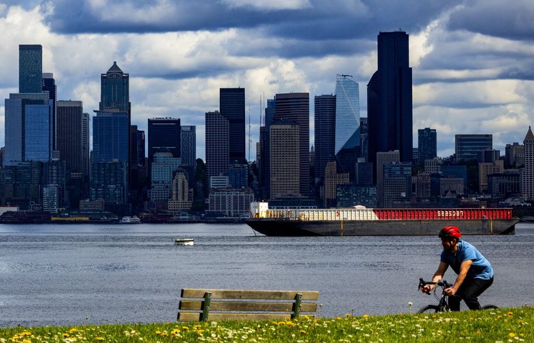 Downtown and big clouds are the backdrop along Alki Trail as spring weather abounds, April 21, 2024 in West Seattle.