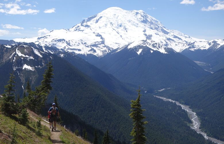 Hikers descend from Crystal Peak under the watchful eye of Mount Rainier.