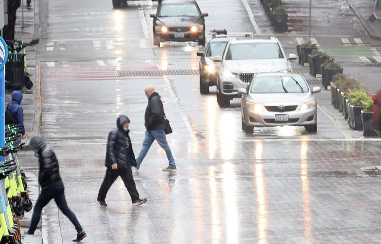 Pedestrians cross the street on a rainy day in Seattle on January 12, 2023.