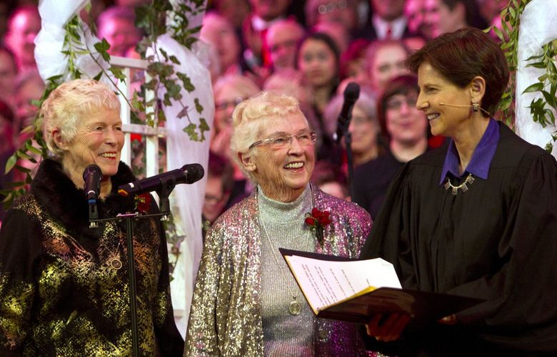 Jane Abbott Lighty, left, and Pete-e Petersen, from Seattle, listen to Judge Anne Levinson during their wedding ceremony at Benaroya Hall in Seattle, Wash., on December 9, 2012.  (© Karen Ducey 2012)