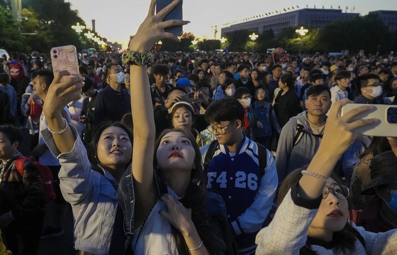 FILE – People take smartphone photos of the crowd on a street near Tiananmen Square as visitors gather to watch a flag-raising ceremony on the National Day in Beijing, Sunday, Oct. 1, 2023. The world’s population is expected to grow by more than 2 billion people in the next decades and peak in the 2080s at around 10.3 billion, a new report by the United Nations said Thursday July 11, 2024. (AP Photo/Andy Wong, File) BGK323 BGK323