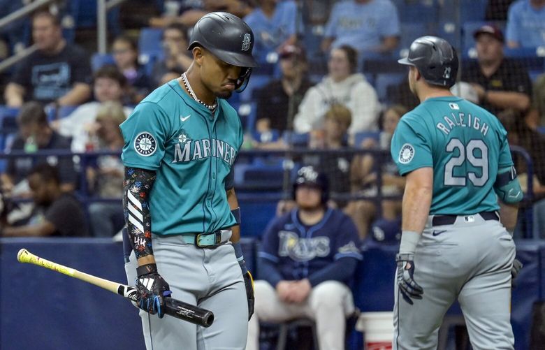 Seattle Mariners’ Julio Rodríguez, left, walks toward the dugout after striking out as Cal Raleigh heads to the plate during a baseball game against the Tampa Bay Rays Tuesday, June 25, 2024, in St. Petersburg, Fla. (AP Photo/Steve Nesius) OTKFLSN103 OTKFLSN103