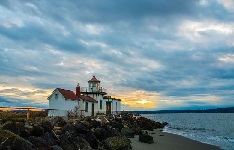 West Point Lighthouse at Discovery Park at sunset on a cloudy day. The sun