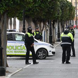 Polizisten stehen in Marbella neben einem Einsatzfahrzeug.