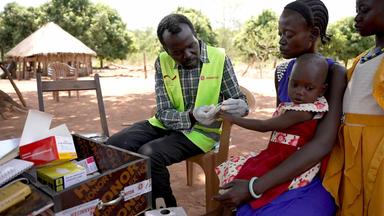 Kang Angui versorgt ein kleines Kind in dem Dorf Makongo Base mit einem Medikament (Südsudan)