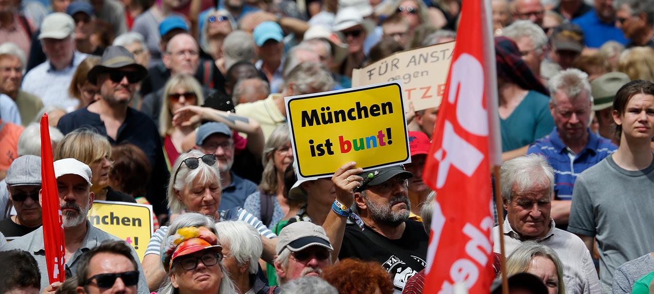 Ein Teilnehmer einer Demo trägt ein Schild mit Aufschrift "München ist bunt!".