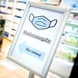 Ein Schild mit der Aufschrift "Maskenausgabe" steht im Eingang einer Apotheke.