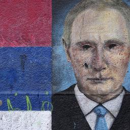Eine Frau geht in Belgrad an einem Graffiti vorbei, das den russischen Präsidenten Wladimir Putin neben den Farben der serbischen Flagge zeigt.