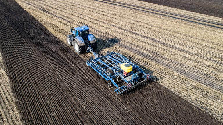 Traktor mit schwerem Grubber arbeitet Gülle in den Boden ein.