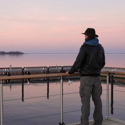 Ein Mann steht auf einem Steg am See