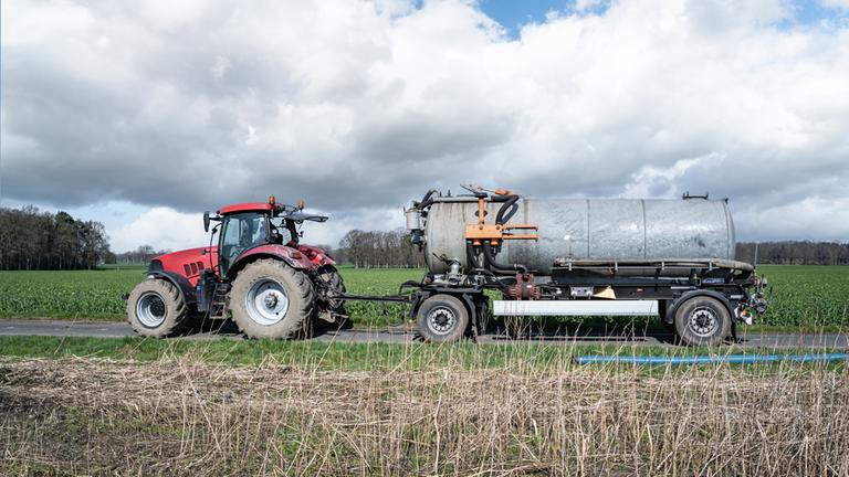 Ein Traktor mit einem Tank bringt Dünger auf eine Feld.