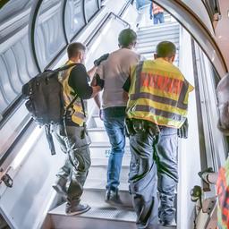 Zwei Polizisten führen einen Mann die Treppe zu einem Flugzeug hoch