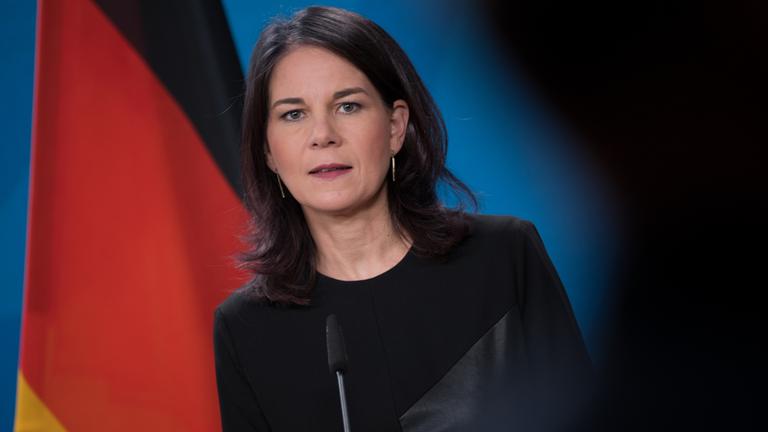 Annalena Baerbock äußert sich vor der Presse, im Hintergrund eine Deutschlandflagge.