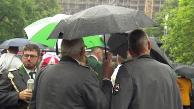 Teilnehmer des Schützenausmarsches in Hannover stehen unter einem Regenschirm.