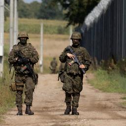 Polnische Soldaten und ein Hund laufen entlang des Grenzzauns an der polnisch-belarusischen Grenze in Usnarz Gorny, Polen.