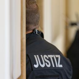 Ein Justizbeamter steht in einem Sitzungssaal).