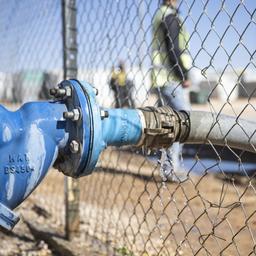  Wasser wird per Schlauch in eine Wasserstation im Saatari Flüchtlingscamp gefüllt.