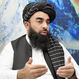 Taliban-Sprecher Zabihullah Mujahid spricht in einem Interview vor einer bunten Wand.