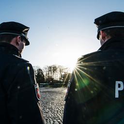 Zwei Polizisten stehen nebeneinander auf einer Straße.