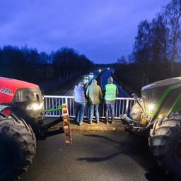Zwei Traktoren stehen auf einer Autobahnbrücke