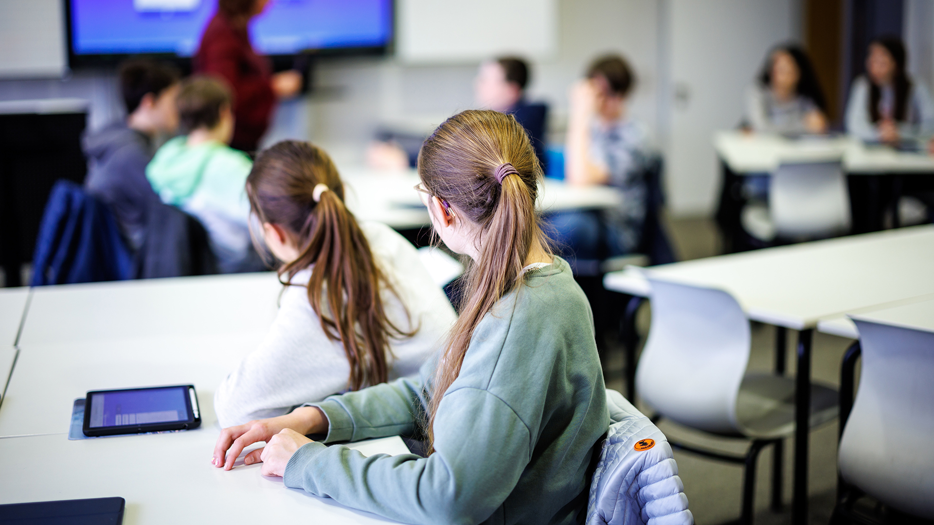 Schüler einer siebten Klasse hören in einem Klassenraum in einer Unterrichtsstunde ihrer Lehrerin zu.