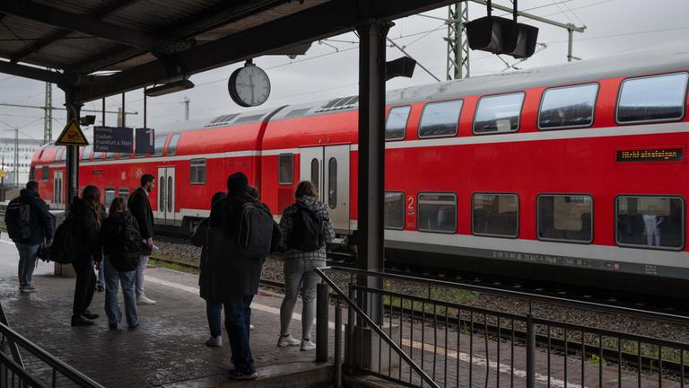 Fahrgäste warten auf eine einfahrende Bahn. 