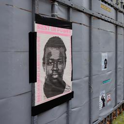 An einem Zaun hängt ein Poster mit einem Bild von Mouhamed Dramé, der in Dortmund nach Polizeichüsen starb.
